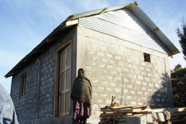 Woman stands in front of a newly built house.