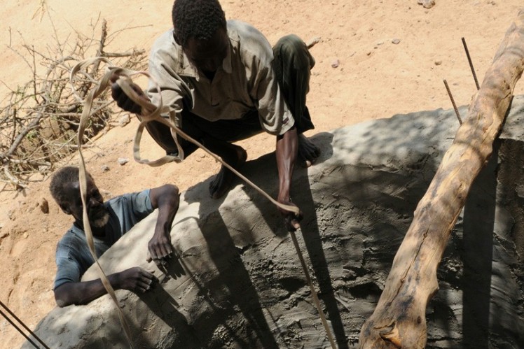 A man pulls a bucket out of a well.