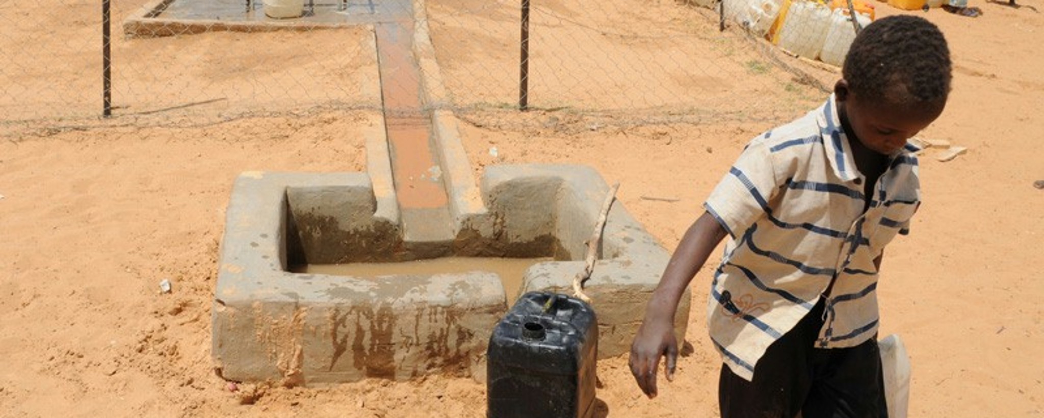 Boy carries a water canister,