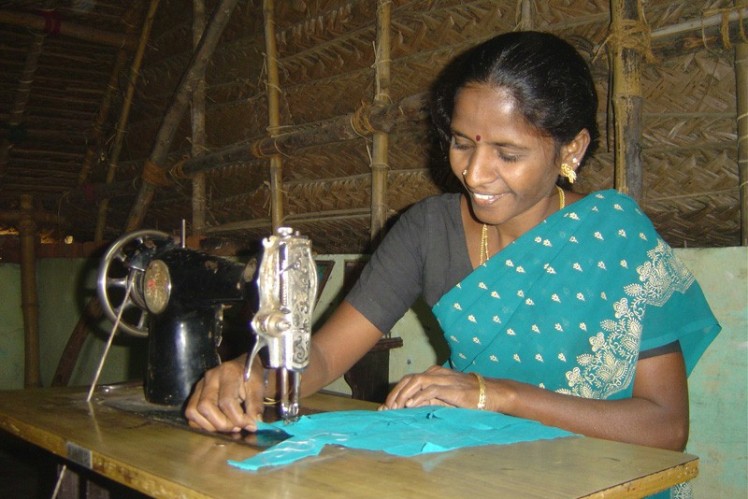 Indian woman sitting at the sewing machine sewing.
