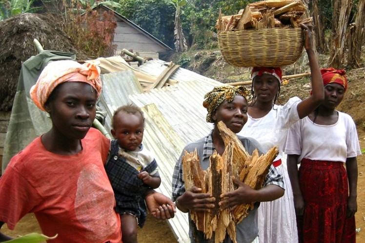 A group of women hold their collected wood in their hands.