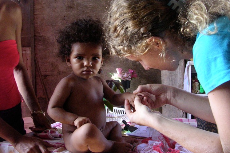 Woman examines the hand of a little girl.