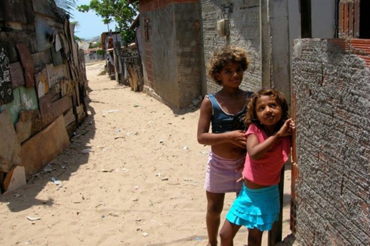 Two girls are leaning against the wall in a slum.