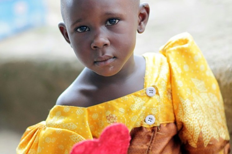 Girl holds a red heart in the camera.
