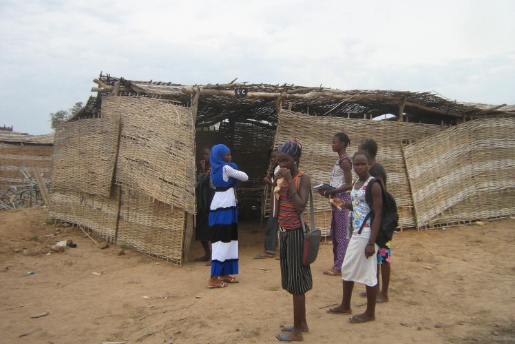 A group of girls stand in front of the classroom with their school bags on their backs.