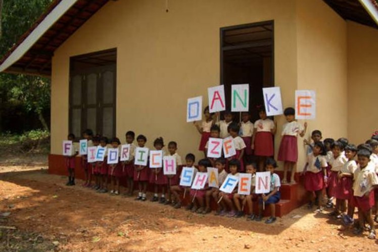 Kinder stehen in einer Reihe und haben Schilder mit einzelen Buchstaben in der Hand.