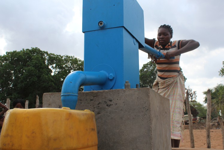 Woman pumping water from a well.